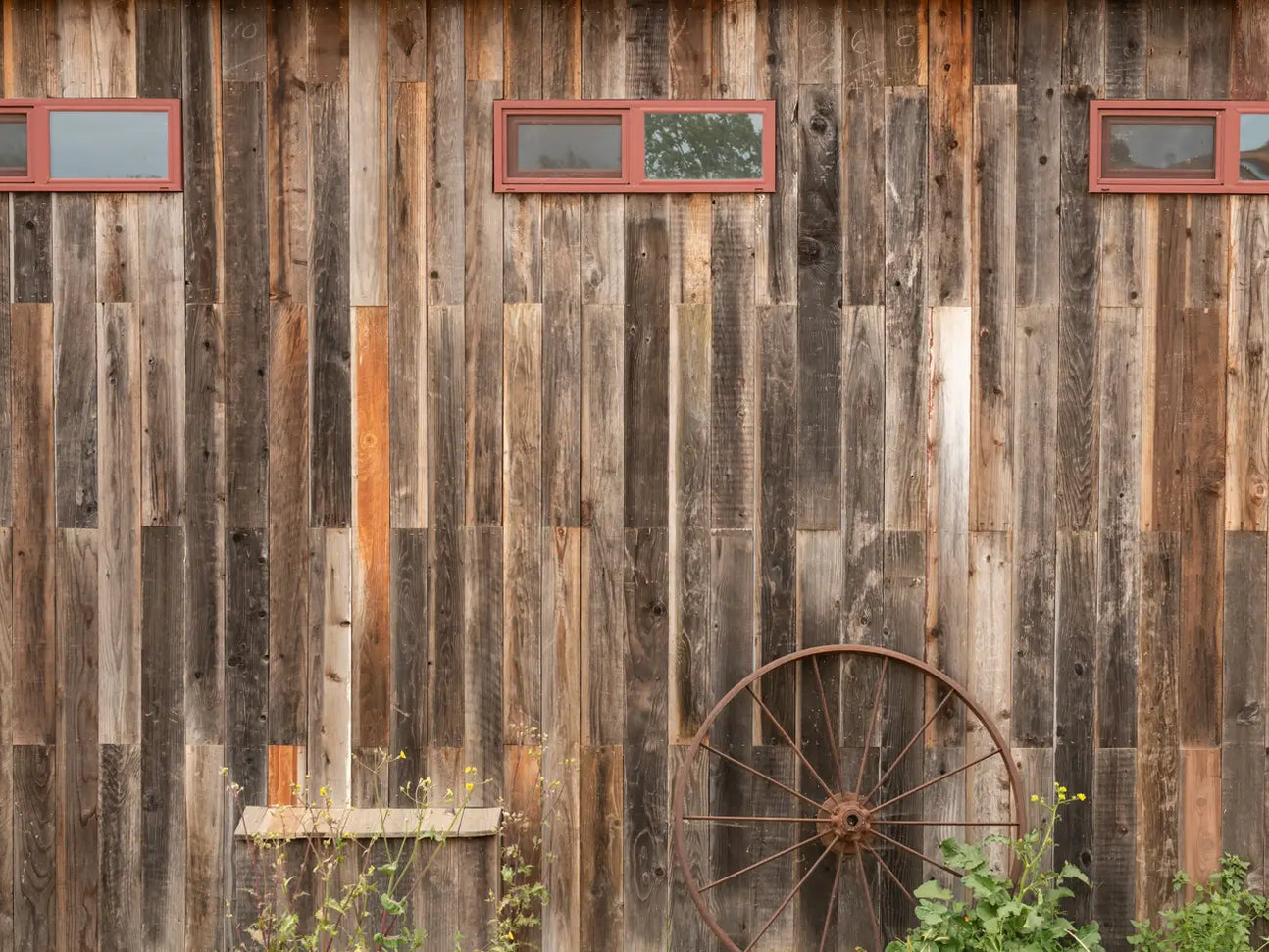 Reclaimed barnwood on a western-style building with a wagon wheel resting against the wood